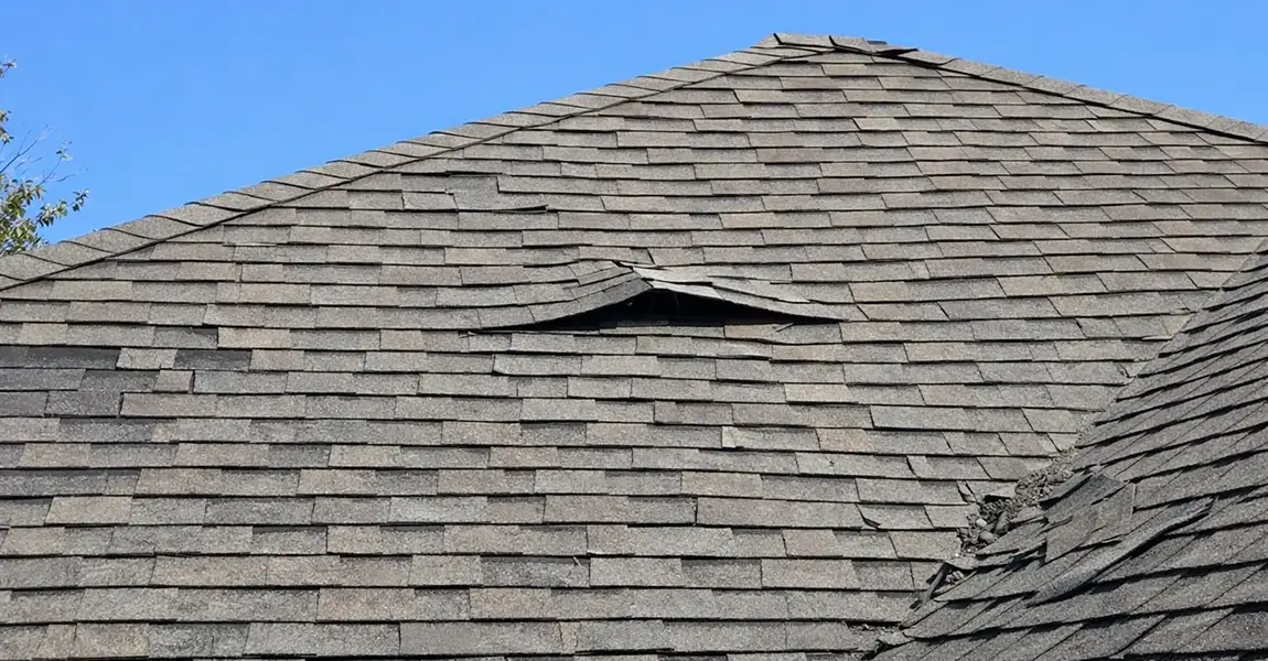 Lifted asphalt shingle showing wind damage roof in Colorado Springs